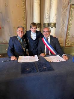 Oberbürgermeister Jürgen Herzing und Bürgermeister Arnaud Péricard unterzeichnen die Bekräftigungsurkunde. In der Mitte Vinzent Müller, einer der jüngsten Teilnehmer beim Galadinner