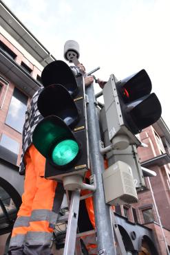  Foto mit einem Monteur, der auf einer Lichtsignalanlage einen Klimasensor montiert