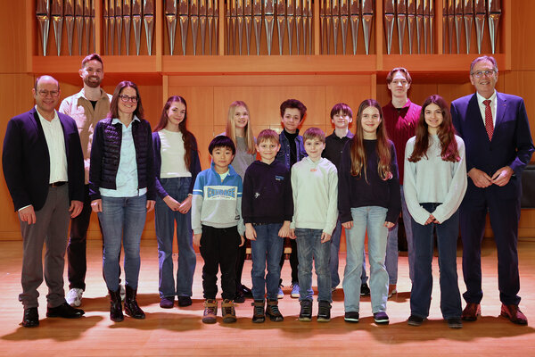 Auf der Bühne stehen von links: Klaus Setzer, pädagogischer Leiter, Sebastian Michaeli, Schlagzeuglehrkraft, Dr. Maria Gramlich, Verwaltungsleitung, und Oberbürgermeister Jürgen Herzing mit den erfolgreichen Schülerinnen und Schülern