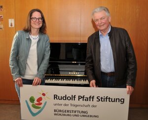 Bild vergr&ouml;&szlig;ern: Musikschulleiterin Dr. Maria Gramlich und Lothar Wegener, Vorstandsmitglied der Rudolf Pfaff Stiftung,  stehen vor dem neuen Klavier und freuen sich gemeinsam.