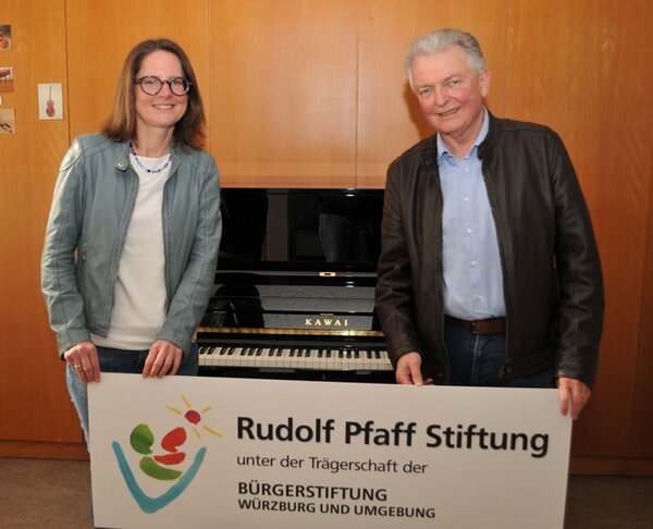 Musikschulleiterin Dr. Maria Gramlich und Lothar Wegener, Vorstandsmitglied der Rudolf Pfaff Stiftung,  stehen vor dem neuen Klavier und freuen sich gemeinsam. 