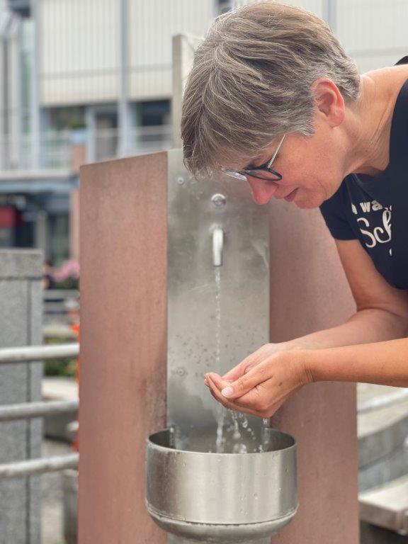 Trinkwasserbrunnen mit Nutzerin