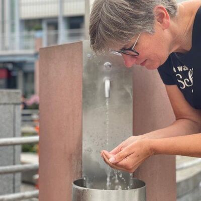 Trinkwasserbrunnen mit Nutzerin