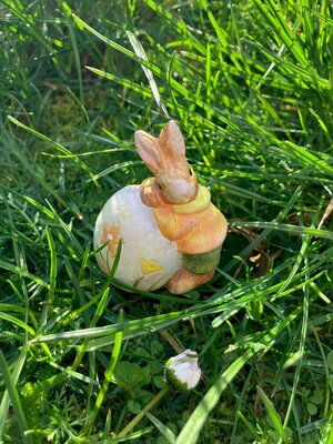 Bild vergr&ouml;&szlig;ern: Osterhase lehnt sich an Osterei, die Figur steht auf einer Wiese.