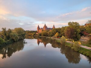 Bild vergr&ouml;&szlig;ern: Blick auf Schloss Johannisburg mit dem Mainufer, das Schloss spiegelt sich im Wasser, Sonnenuntergang