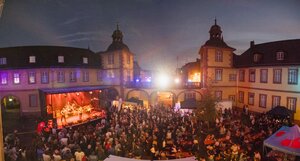 Bild vergr&ouml;&szlig;ern: Festival „Rock the Archive“: Bühne mit Band und viele Zuschauer*innen im Innenhof vom Schönborner Hof. Sommernachtsstimmung.