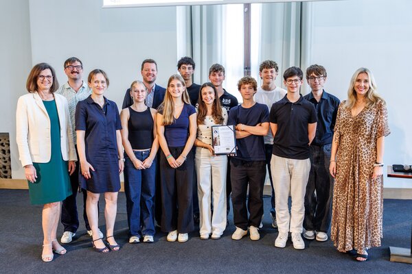 Gruppenfoto: Ilse Aigner, Bayerische Landtagspräsidentin, und Anna Stolz, Bayerische Kultusministerin, überreichen Schülern der 10. Klassen des Hermann-Staudinger-Gymnasiums aus Erlenbach den 2. Preis im Rahmen des landesweiten Wettbewerbes „Erinnerungszeichen“. 