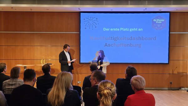 Leonhard Kugler, Geschäftsführer des Zentrums für Digitale Souveränität der Öffentlichen Verwaltung GmbH (ZenDiS) und Mitglied der Jury überreicht den Goldpreis an Doris Rebitzer vom Amt für IT und Digitalisierung. 